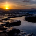 Waves crashing on rocks with pools water at sunset Royalty Free Stock Photo