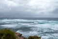 Waves crashing on the rocky coastline with dark ominous clouds