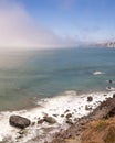 Waves crashing on a rugged coastline with heavy fog in the background. San Fransisco, California.
