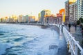 Waves crushing with the wall in San Lorenzo beach in Gijon, Asturias, Spain, with buildings and the promenade at the background