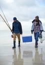 Waves, fishing and men walking on beach together with cooler, tackle box and holiday conversation. Ocean, fisherman and Royalty Free Stock Photo