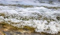 Waves and Foam from the water on the rocks on the lake shore Royalty Free Stock Photo