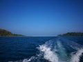 Waves generated by speed boat in blue ocean under blue sky