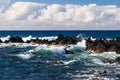 Waves on Hawiian shore; volcanic rocks in surf. Pacific in distance, with blue sky and clouds. Royalty Free Stock Photo