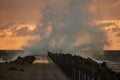 Waves hit the pier in front of the sunset at Nr. Vorupoer at the North Sea Coast in Denmark