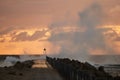 Waves hit the pier in front of the sunset at Nr. Vorupoer at the North Sea Coast in Denmark