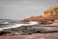 Waves hitting rock coast with different colors from red to yellow in the Kalbarri National Park Australia partly in black and