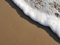 Waves lapping against sand on the California coast. Sea foam and sandy beaches in summer sunlight for travel blogs, website banner Royalty Free Stock Photo