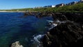 Waves lapping on rock in foreground with view of Fistral bay and distant beach, Cornwall