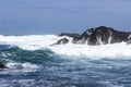 Waves crash onto volcanic rocks.