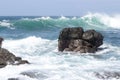 Waves crash onto volcanic rocks.