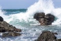 Waves crash onto volcanic rocks.