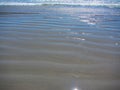 Waves and ripples rolling inshore along a sandy beach Royalty Free Stock Photo