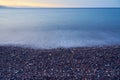 Waves rolled on the pebble beach with the sunset horizon in the background. Royalty Free Stock Photo