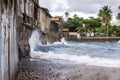 Waves of rough sea crashing into the base and walls of houses