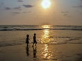 Sillhoutte image of a boy and a girl playing in sea on a background of nice Sunset.
