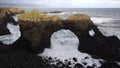 Waves smashing in slow motion through Gatklettur or Hellnar Arch