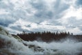 Waves and splashes of mountain river on background of forest, rocks and dramatic sky. Forest river water landscape. Wild river in Royalty Free Stock Photo
