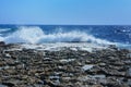 Waves with splashes roll onto rocky shore Royalty Free Stock Photo