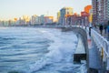 Waves splashing against the wall in San Lorenzo beach in Gijon, Asturias, Spain, with the promenade and buildings in one side