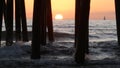 Waves splashing under pier, sunset in Oceanside, California USA. Ocean water, sun and wooden piles. Royalty Free Stock Photo