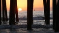 Waves splashing under pier, sunset in Oceanside, California USA. Ocean water, sun and wooden piles. Royalty Free Stock Photo