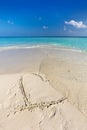 Waves wash away a heart drawn on sand of a tropical beach Royalty Free Stock Photo