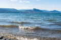 Waves washing onto Three Mile Beach at Okanagan Lake with view of Giant`s Head Mountain and blue sky