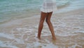 Waves washing woman legs at calm shore. Slim girl playing touching ocean sand in