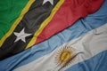 waving colorful flag of argentina and national flag of saint kitts and nevis