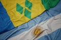 waving colorful flag of argentina and national flag of saint vincent and the grenadines