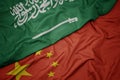 waving colorful flag of china and national flag of saudi arabia