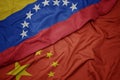 waving colorful flag of china and national flag of venezuela