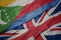 waving colorful flag of great britain and national flag of comoros