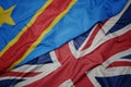 waving colorful flag of great britain and national flag of democratic republic of the congo