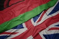 waving colorful flag of great britain and national flag of malawi