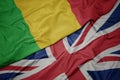 waving colorful flag of great britain and national flag of mali