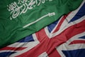 waving colorful flag of great britain and national flag of saudi arabia