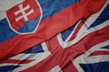 waving colorful flag of great britain and national flag of slovakia