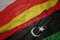 waving colorful flag of libya and national flag of south ossetia