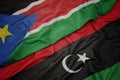 waving colorful flag of libya and national flag of south sudan