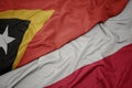 waving colorful flag of poland and national flag of east timor