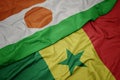 waving colorful flag of senegal and national flag of niger