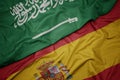 waving colorful flag of spain and national flag of saudi arabia