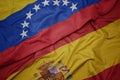 waving colorful flag of spain and national flag of venezuela