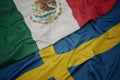 waving colorful flag of sweden and national flag of mexico