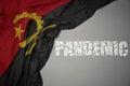waving colorful national flag of angola on a gray background with broken text pandemic. concept Royalty Free Stock Photo