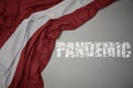 waving colorful national flag of latvia on a gray background with broken text pandemic. concept