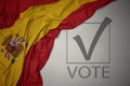 Waving colorful national flag of spain on a gray background with text vote. 3D illustration