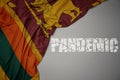 waving colorful national flag of sri lanka on a gray background with broken text pandemic. concept